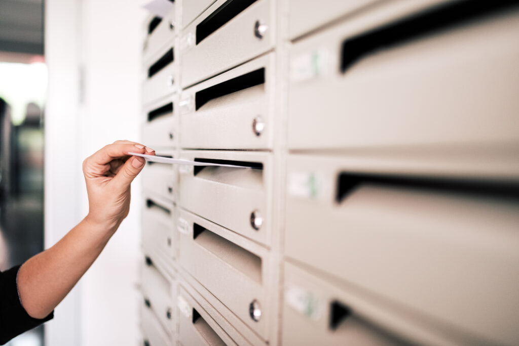 sending postcard. close up of woman's hand posting a letter.